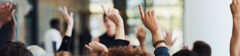 People with hands raised during presentation